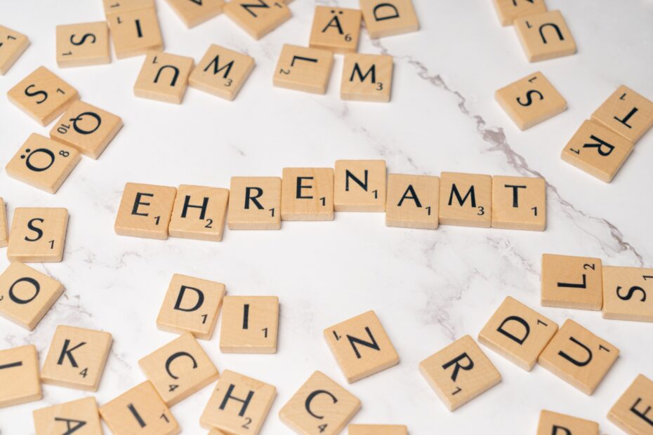 Das Wort "Ehrenamt" wird mit Scrabble-Steinen gebildet. Rundherum liegen mehrere einzelne Scrabblesteine.